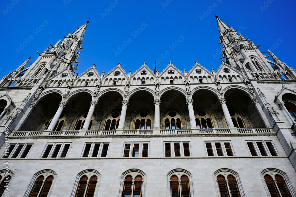 Obraz premium elevation detail of the neo gothic stone parliament building in budapest along the danube river. arched windows. tall tower with turrets. famous historic landmark building. popular tourist destination