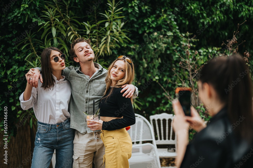 Fototapeta premium Friends having fun while posing for a photo outdoors, framed by lush green foliage. Capturing joyful and carefree moments at a casual garden gathering, emphasizing friendship and togetherness.