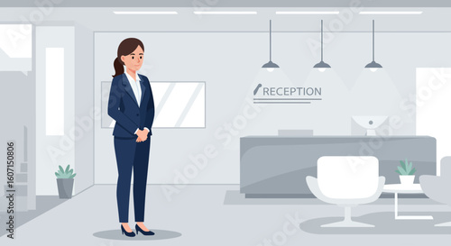 Woman in a blue suit stands in a modern reception area with a desk and chair.