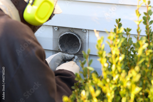 Fotografía A Portrait Of A Black Man Replacing A Mesh Covering Over A Dryer Vent