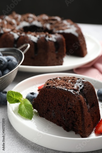 Wallpaper Mural Piece of delicious chocolate bundt cake with mint and blueberries on light grey textured table against black background, closeup Torontodigital.ca