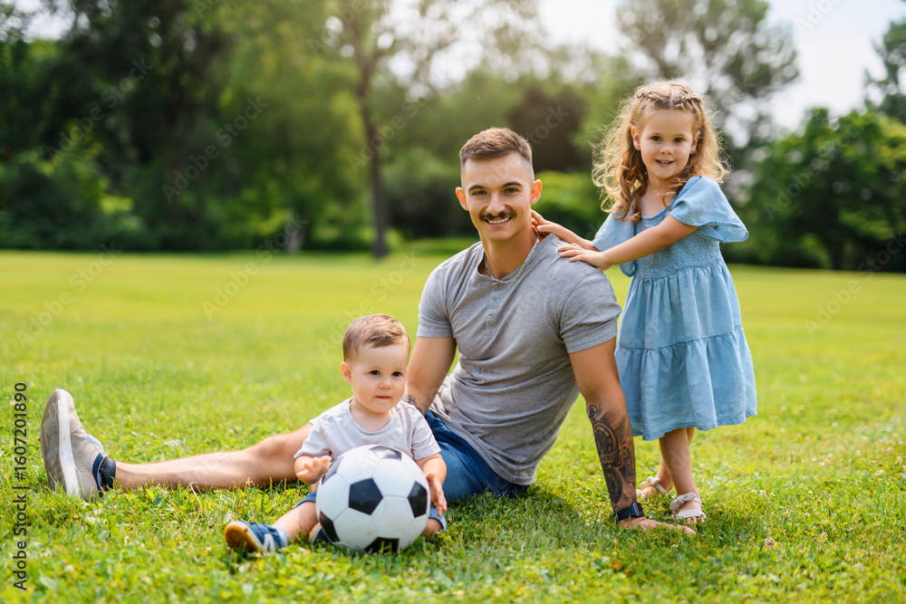 Fototapeta premium Young father with his little son and daughter playing soccer