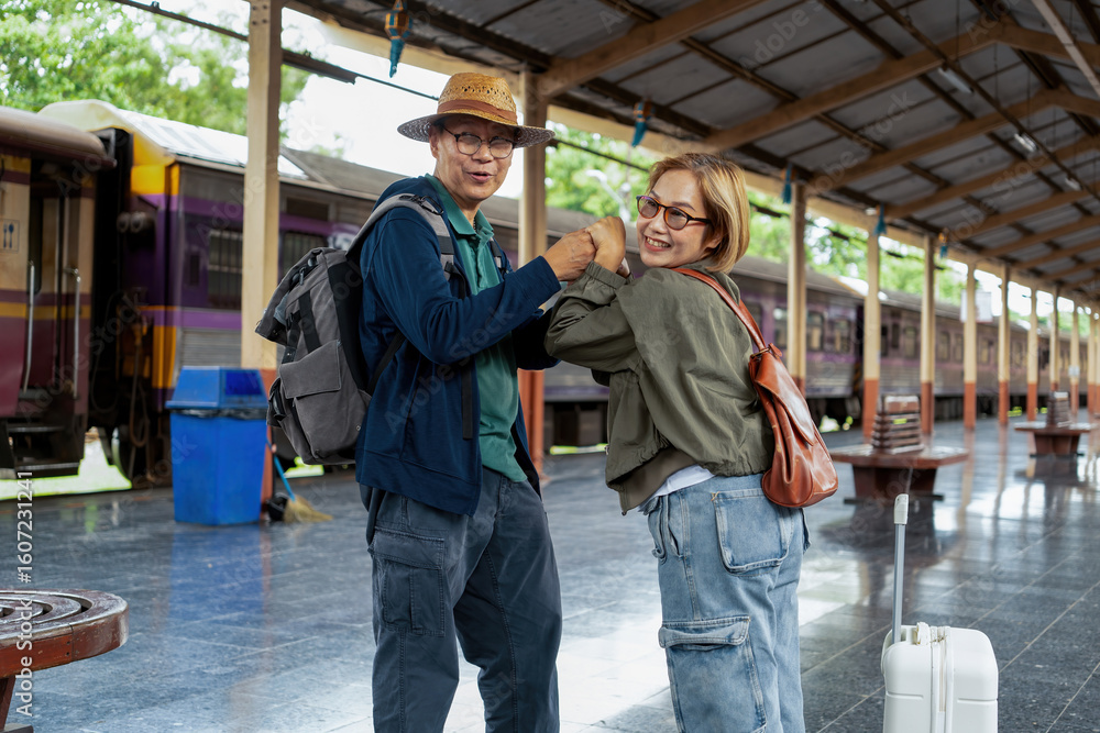 Fototapeta premium Happy Asian senior boarding a train at the station