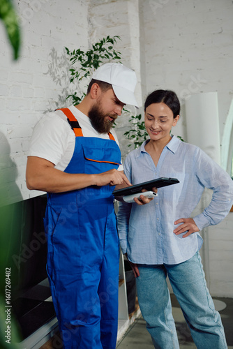 Принти на полотні Technician smiling while demonstrating repair details to homeowner on tablet inside