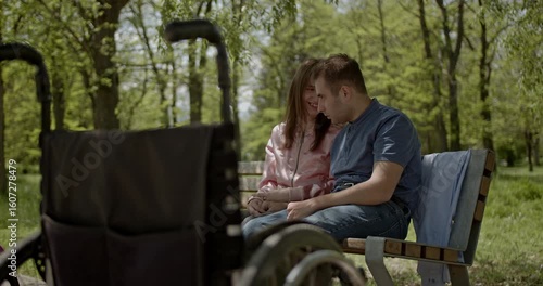 A loving couple shares a tender moment on a park bench, demonstrating profound support and connection despite disability. Their affection radiates a beautiful bond of understanding and care in nature.