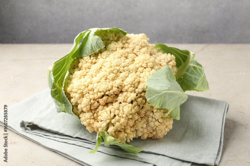 Fresh cauliflower with green leaves on light grey table, closeup Fresh cauliflower with green leaves on light grey table, closeup