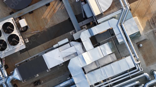 Aerial top-down view of industrial HVAC and ventilation system with ducts and units on flat rooftop of a modern commercial building.