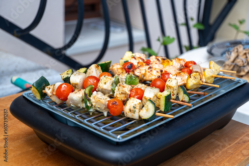 Brochettes de poulet et légumes grillées au barbecue électrique lors d’un repas estival en plein air