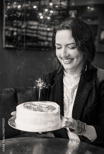 Smiling woman holding a birthday cake with a sparkler