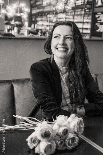 Smiling woman with flowers in a cafe, black and white portrait