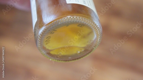 Bottle bottom with alcohol remnants, lit by soft light, showing liquid and sediment on glass surface
