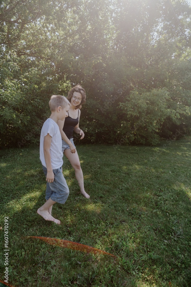 Fototapeta premium A mother and her son with hearing aids launch a paper airplane in a park, a heartwarming moment of inclusive play and bonding in nature. Perfect for disability awareness and family lifestyle content