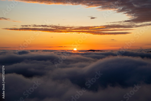 golden sunset over the clouds or fog of tuscany in a view from Montepulciano into the backlight of the going sun
