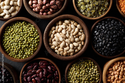 An assortment of dried beans and legumes in wooden bowls, viewed from above
