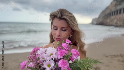 Woman holding pink flower bouquet on beach

