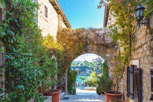 Charming stone alley with arch and sea view in Ulcinj Old Town on sunny day, Montenegro