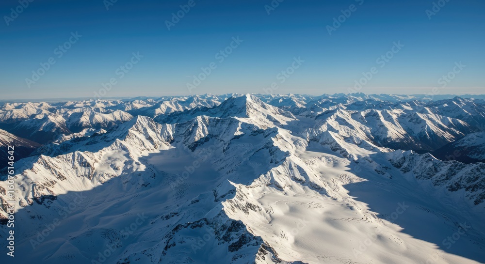 Naklejka premium Majestic Snow-Capped Mountain Range Under Clear Blue Sky, Aerial View