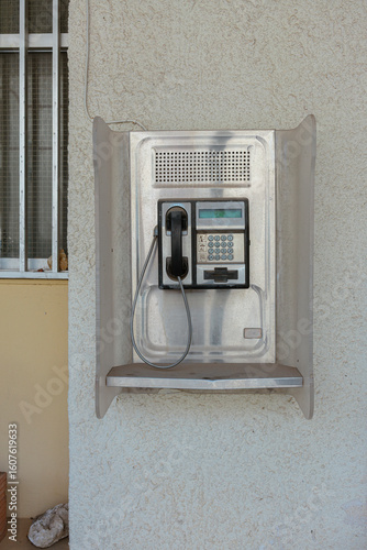 Obraz na plátně Public payphone mounted on textured stone wall representing traditional telecomm