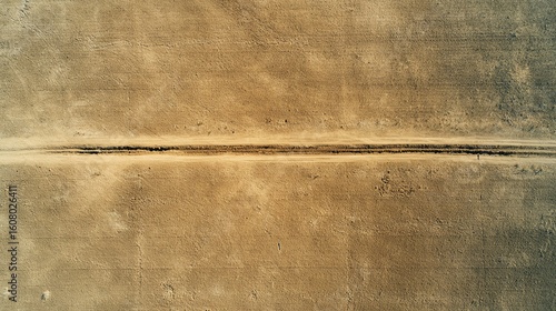 Aerial view of a barren desert landscape with a narrow road cutting through the dry, sandy terrain.