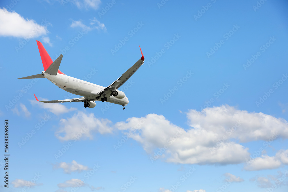 Obraz premium Airplane flying in beautiful blue sky with clouds