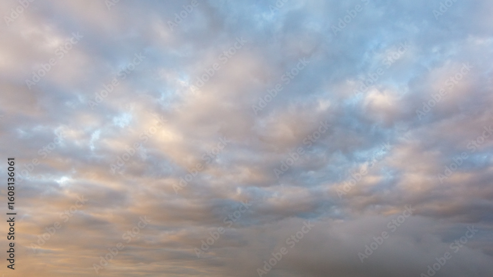 Obraz premium Expansive sky filled with soft, fluffy clouds in various shades of blue and gray, creating a serene atmosphere and inviting tranquility for nature lovers and photographers alike
