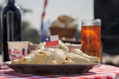 Chilean Independence Day: Traditional empanadas with Chilean flag and mote con huesillo on a red tablecloth