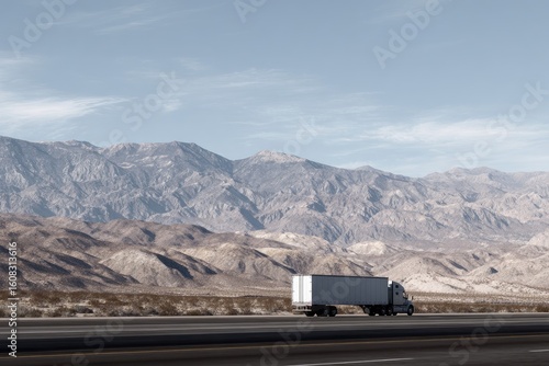 Semi-truck traversing desert highway, mountain backdrop