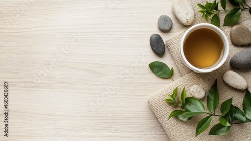 a peaceful zen flat lay with yoga mat corner, smooth stones, green leaves, and a cup of herbal tea on a light wood surface, evoking calm and self-care
