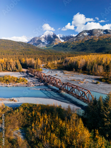 Aerial scenic view of rail road bridge over glacial river in Alaska during autumn time.