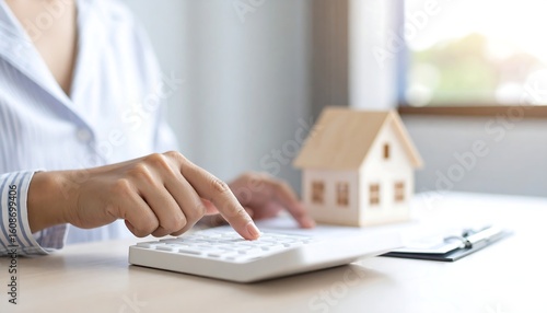 Woman using calculator near miniature house