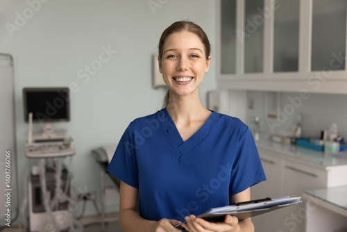 Tableau sur toile Positive ultrasound diagnosing doctor in blue scrubs posing in office in clinic,
