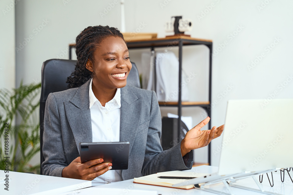 Fototapeta premium Professional Woman Communicating During Online Meeting, Smiling While Using Technology In Modern Office Setting, Depicts Remote Work And Virtual Communication Concepts.
