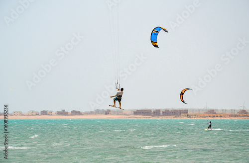 Kitesurfers training on the Red Sea in Hurghada, Egypt. Sunny weather, clear water and dynamic motion create a vibrant beach scene full of energy and action.
