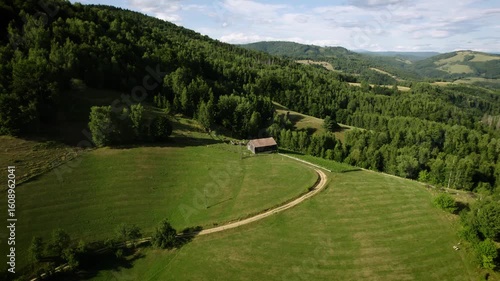 Beautiful Slovak nature. Small wooden house on a hill surrounded by green forests, old farm. Drone video.