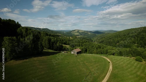 Beautiful Slovak nature. Small wooden house on a hill surrounded by green forests, old farm. Drone video.