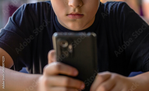 Boy with a serious face communicates on Internet. Child gadget addiction. Child, teenager or preteen mobile phone. Mobile addiction, digital dependence concept
