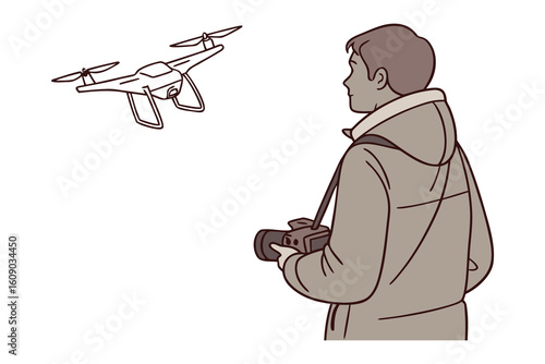 Man in a jacket controls a drone with a camera attached while looking up at the flying device