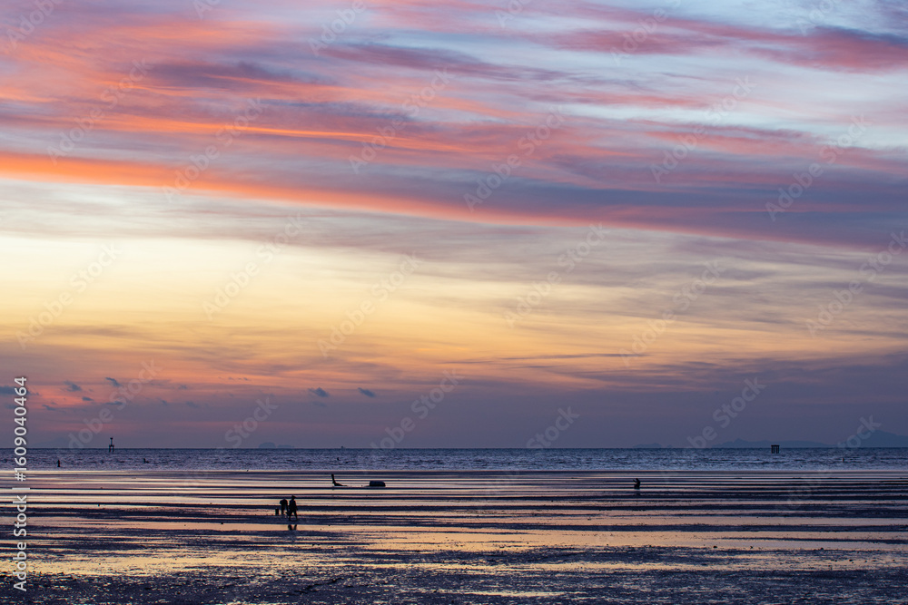 Fototapeta premium A stunning scene of a vivid sunset with pink and orange hues illuminating the sky over Karon beach Phuket. The serene water create a peaceful and atmospheric view