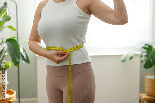 Young woman measuring her waistline