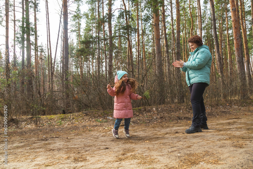 Fototapeta premium Grandmother with granddaughter walking in nature in the forest