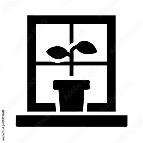 Potted plant growing on windowsill in silhouette with natural light  