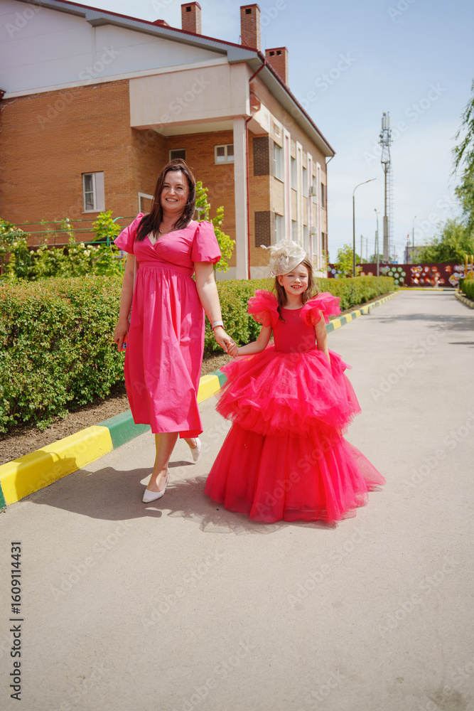 Fototapeta premium Happy well-dressed family on a walk. Mom and little daughter/