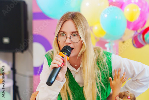 Konstfotografi A funny young woman with a microphone is leading a children's party