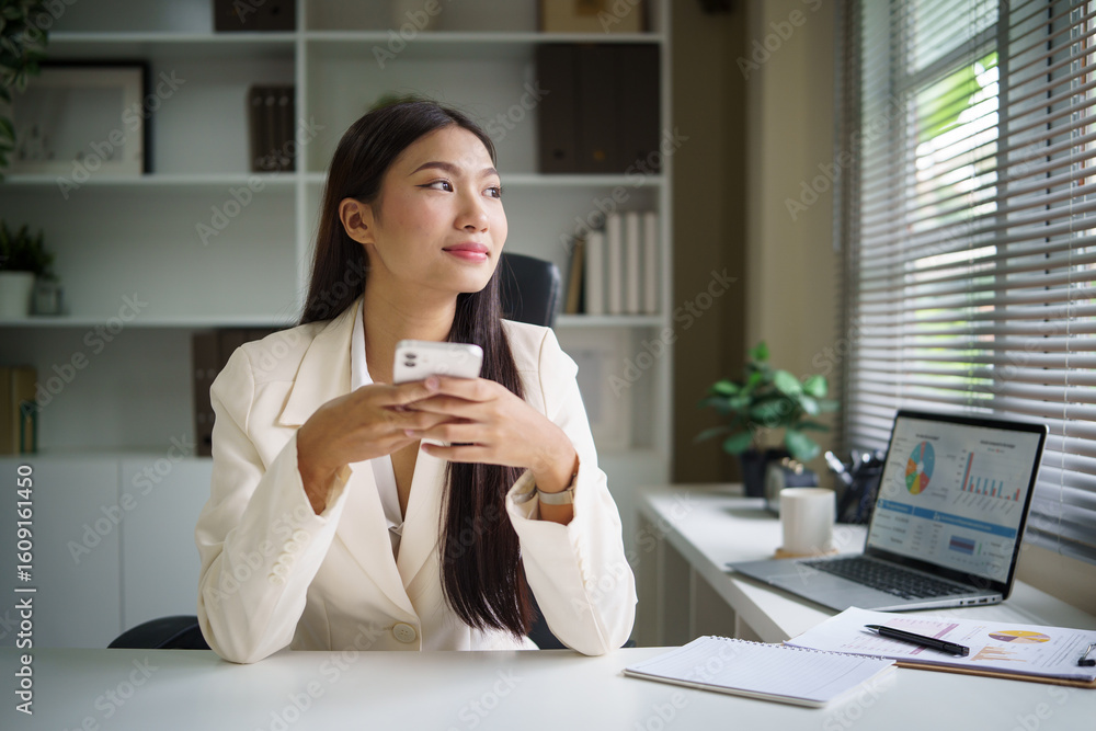 Thoughtful businesswoman holding smartphone, gazing out the window with a calm and reflective expression at office desk. Thoughtful businesswoman holding smartphone, gazing out the window with a calm and reflective expression at office desk.
