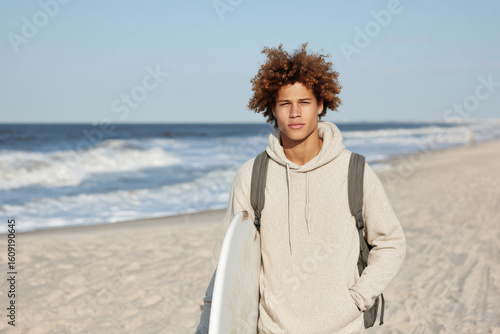 teenager wearing cozy hoodie and carrying backpack stands confidently on beach radiating energy