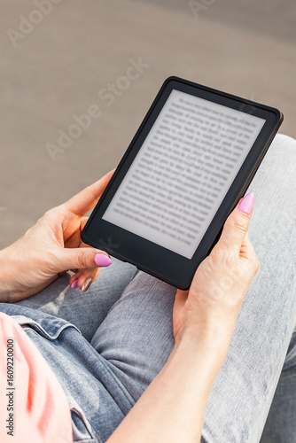 woman reading e-book sitting on bench. man reading an e-book. Vertical photo