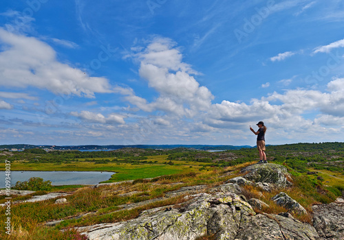 Woman take a picture from the coast of Vallda Sandö, nature reserve, Sweden