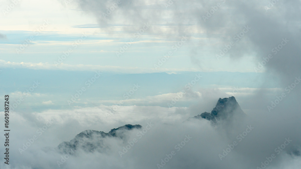 Obraz premium Clouds covering the mountain revealed only the peak. The clouds gradually moved higher from the other side. The light from the sky in the distance. Phu Thap Boek Phetchabun Thailand.