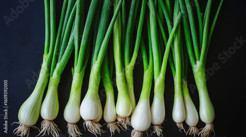 Fresh green onions arranged on a dark surface.
