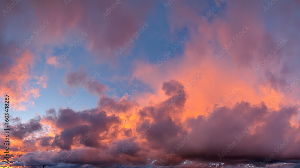 Fototapeta premium Dramatic sunrise with gradient orange and purple clouds, creating a panoramic abstract sky view.